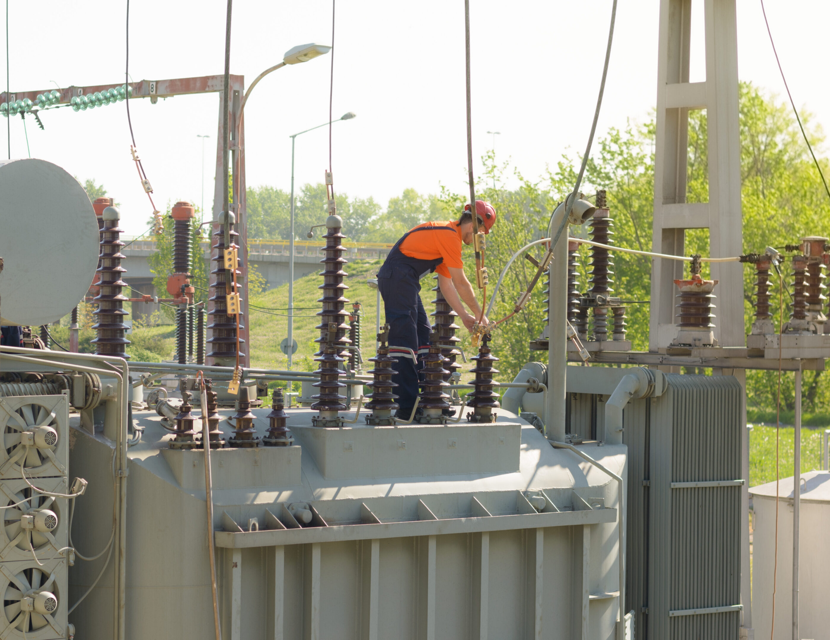 Worker inspecting electrical transformer outdoors.
