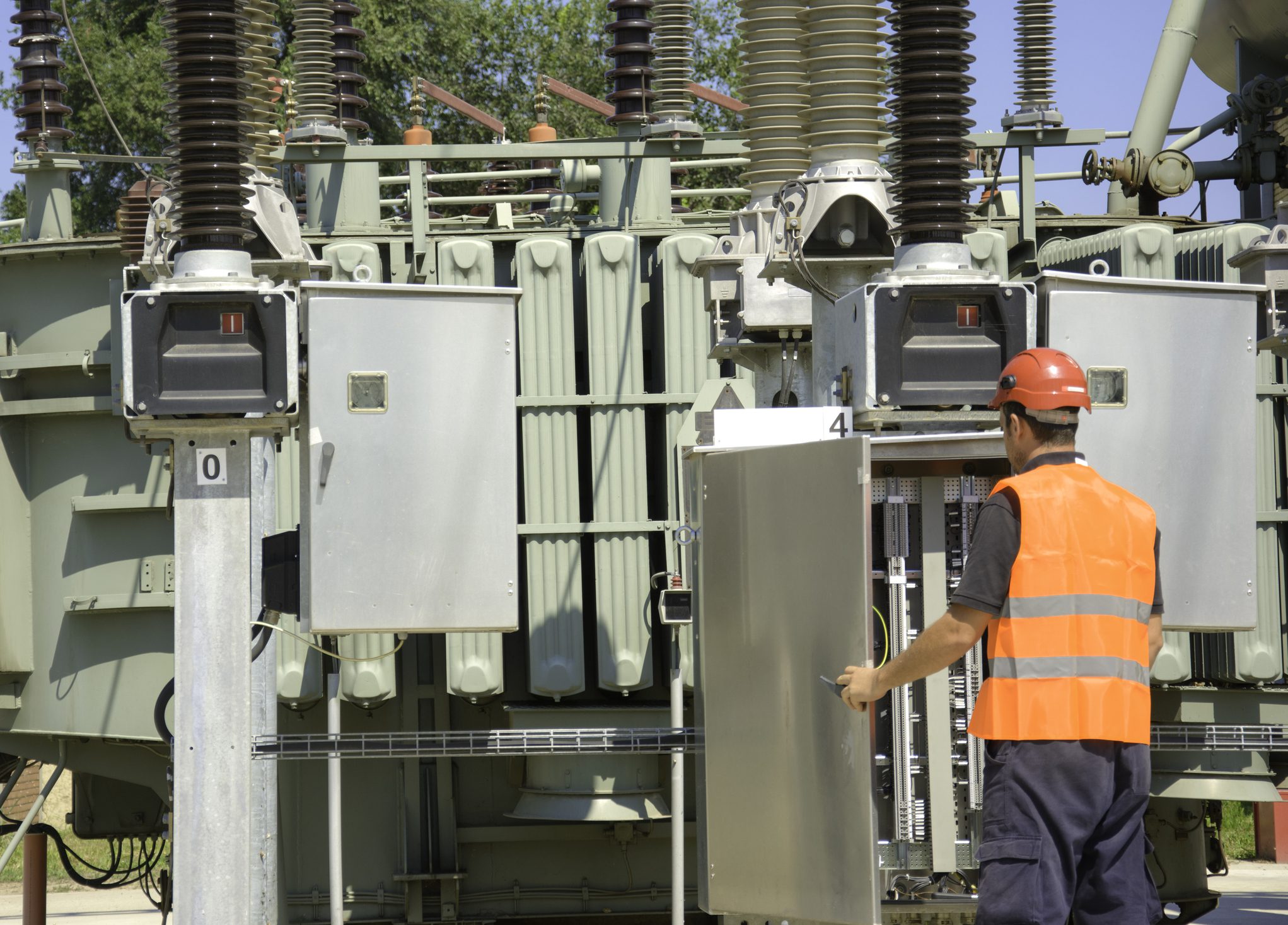 Worker inspecting electrical substation equipment.