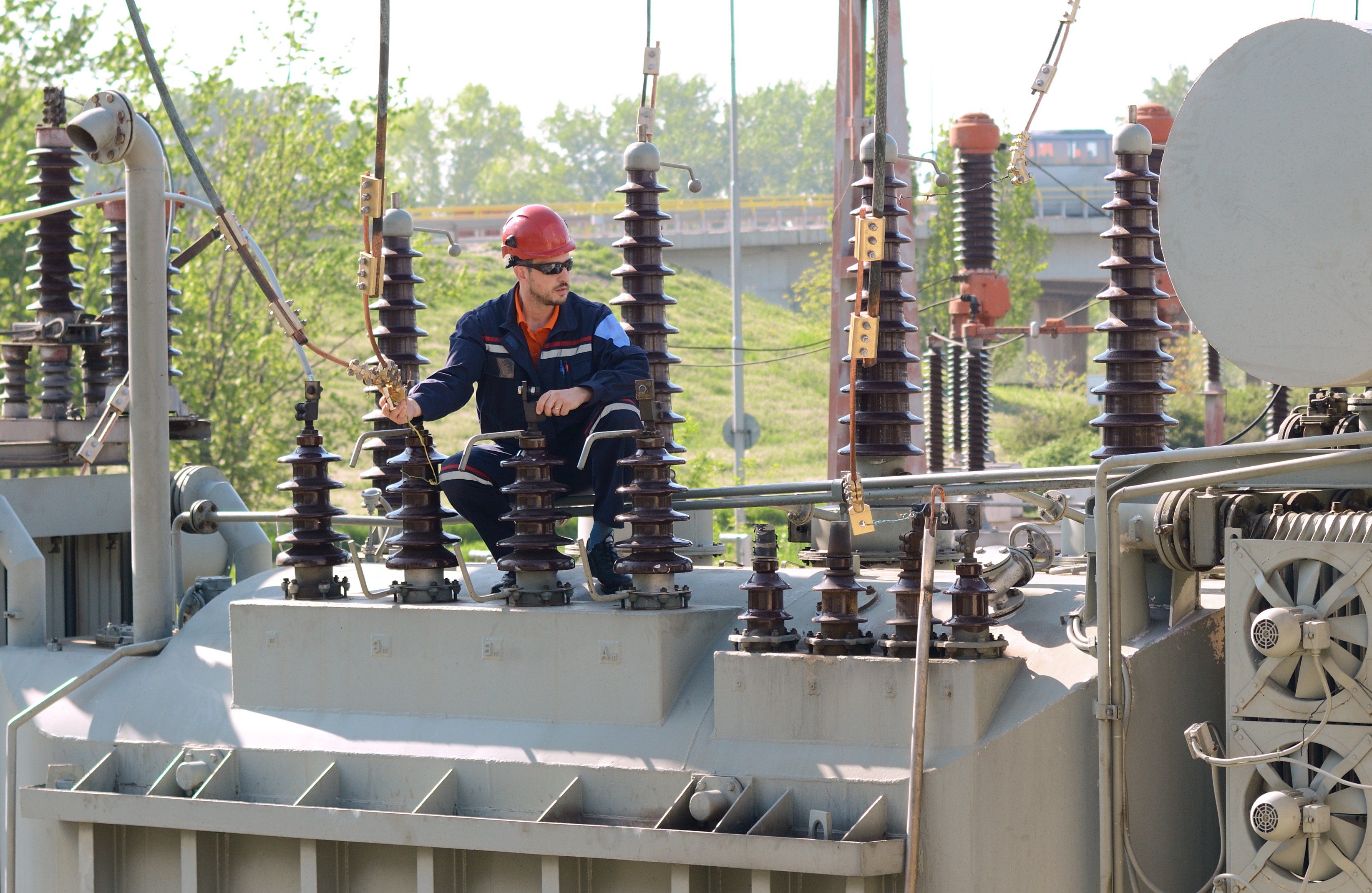 Worker maintaining electrical substation equipment outdoors.